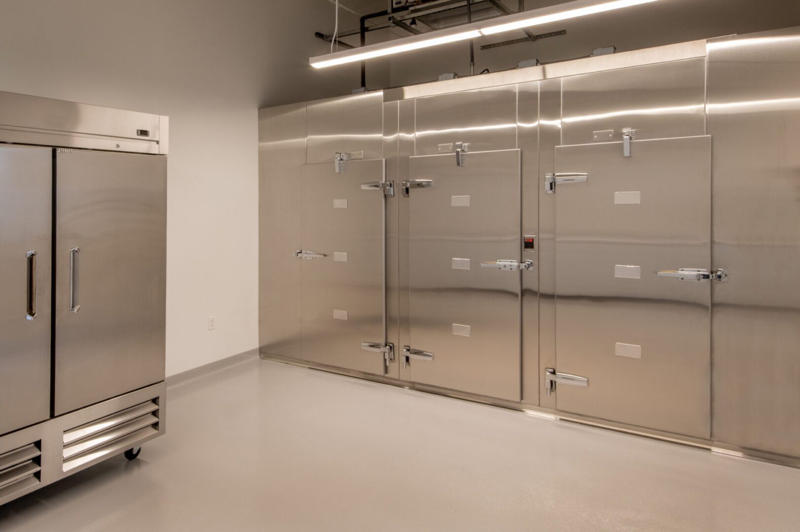 A room with stainless steel walls and a refrigerator.